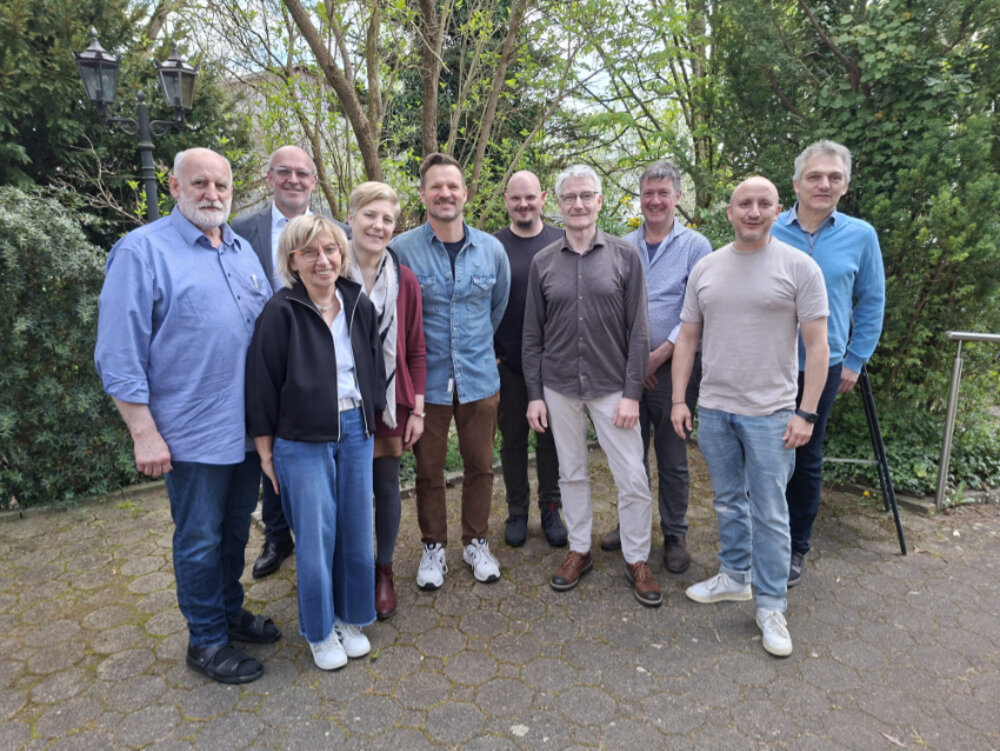 Ein Gruppenfoto von Männern und Frauen in der grünen Natur. Alle lächeln.