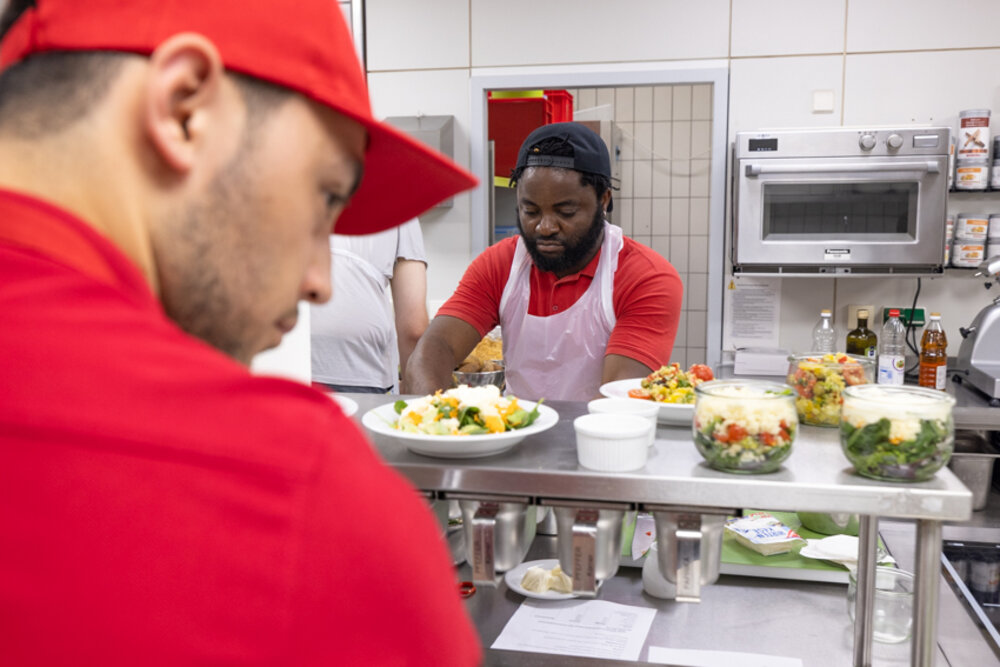 Blick in die Küche: Zwei junge Männer bereiten Bowls zu