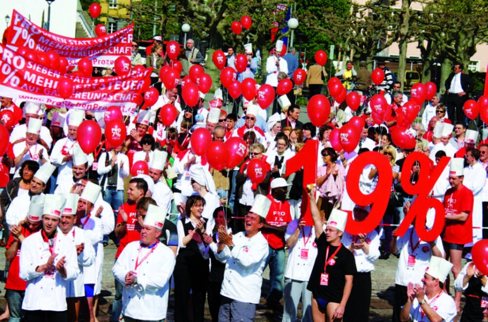 Foto einer Demonstration mit vielen Menschen, die rote Luftballons in den Händen halten.