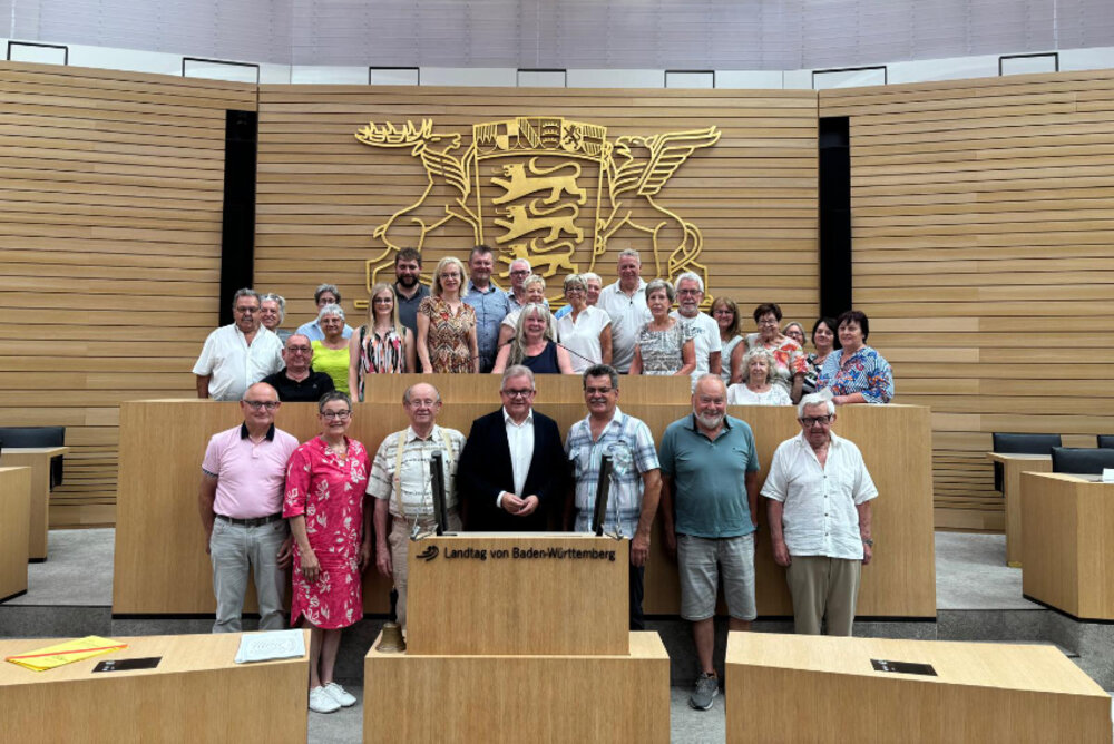 Eine Gruppe posiert für ein Foto im Plenarsaal des Landtags Baden-Württemberg