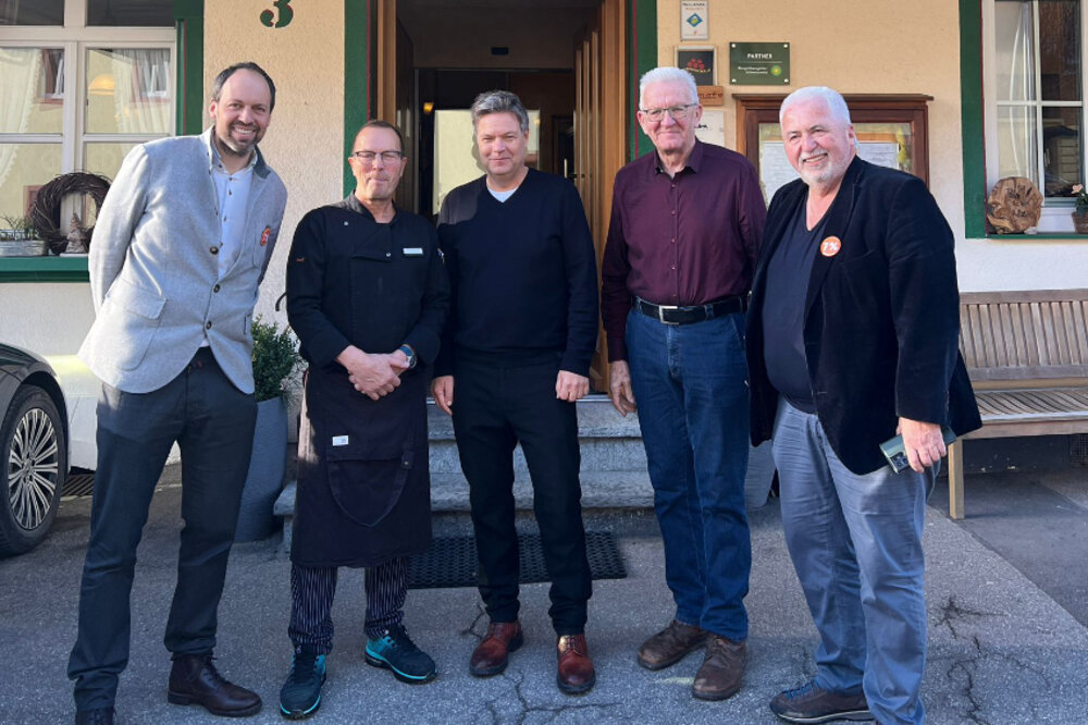 Foto von fünf Männern vor einer Gaststätte.