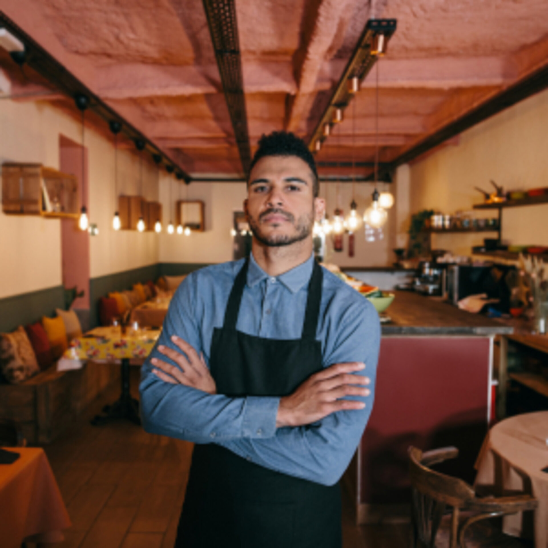 Ein Mann in der Berufskleidung des Gastgewerbes steht mit ernster Miene in einem Restaurant