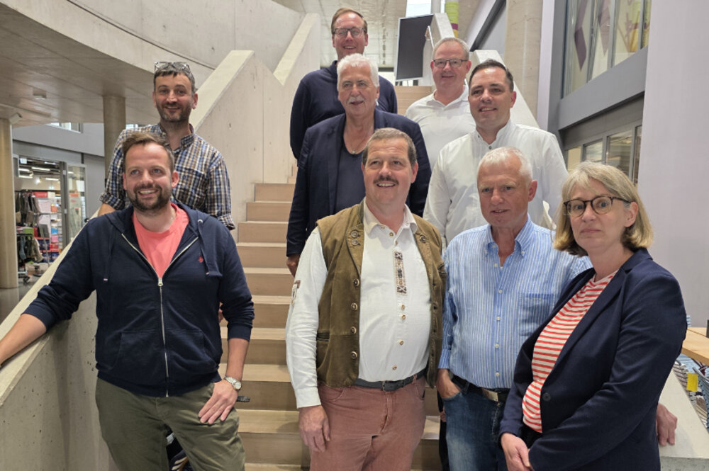 Ein Gruppenfoto auf bzw. vor einer Treppe von acht Männern und einer Frau