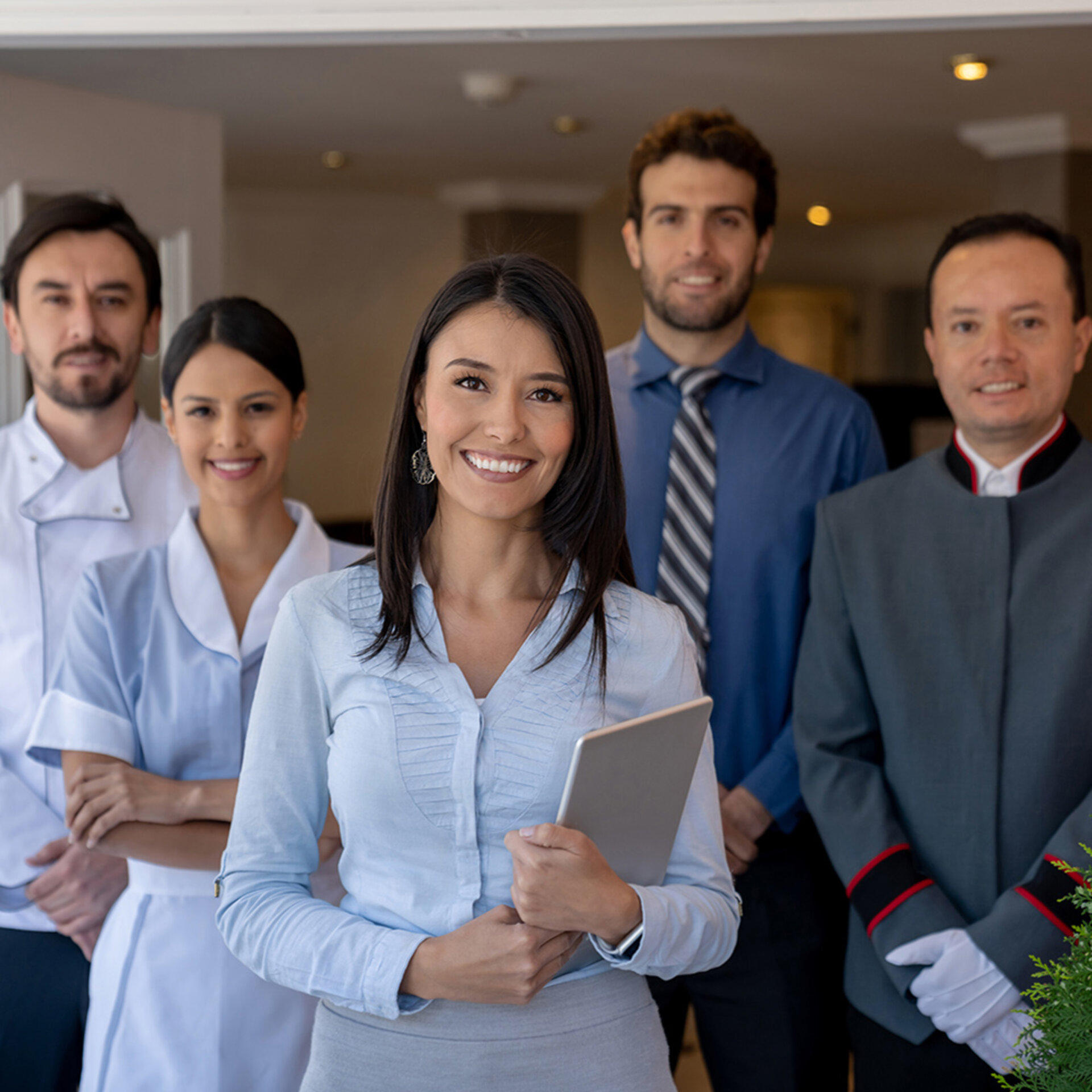 Abbildung von fünf Personen in Arbeitskleidung, die im Eingangsbereich eines Hotels stehen